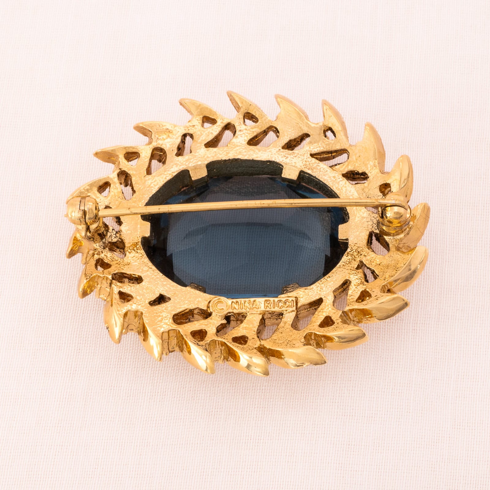 Nina-Ricci-ovale-Brosche-blauer-Kristall-vergoldete-Rückseite-Signatur
